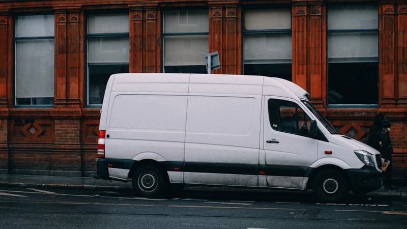 White courier van parked against a red-brick Manchester building, ready for collection