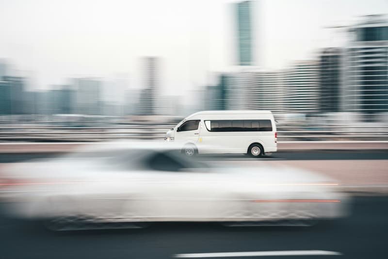 Courier van moving at speed through a city street, motion-blurred buildings behind